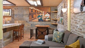 A cozy interior with a stone wall, a mural of musicians, a bar area, and a seating arrangement. - Vacation Home "Casa Barriguita" with Mountain View, Private Pool & Wi-Fi (Yaiza)