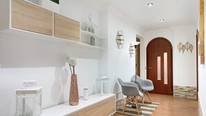 A modern living room with a white console table, wooden shelves, a patterned chair, and a wooden door. - Vacation Home "Casa Barriguita" with Mountain View, Private Pool & Wi-Fi (Yaiza)