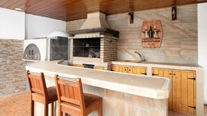 A kitchen with a stone backsplash, wooden cabinets, and a built-in oven. - Vacation Home "Casa Barriguita" with Mountain View, Private Pool & Wi-Fi (Yaiza)