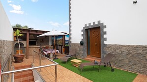 A patio with outdoor furniture, a wooden door, and a stone wall. - Vacation Home "Casa Barriguita" with Mountain View, Private Pool & Wi-Fi (Yaiza)