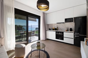 A modern kitchen with a large sliding glass door to a balcony, a black refrigerator, and a microwave.
