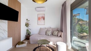 A modern living room with a sofa, a small table, a potted plant, and a large window with a view. - Apartment 'Mella Roa Emer' with Sea View, Wi-Fi and Air Conditioning (???????)