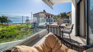 A balcony with a view of the sea, a dining table, and a wicker chair. - Apartment 'Mella Roa Emer' with Sea View, Wi-Fi and Air Conditioning (???????)