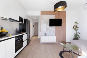 A modern kitchen with built-in appliances, a flat-screen TV, and a dining area with a table and chairs.