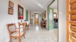 Un couloir comprenant un coin repas, des chaises, une table, une lampe et un miroir.