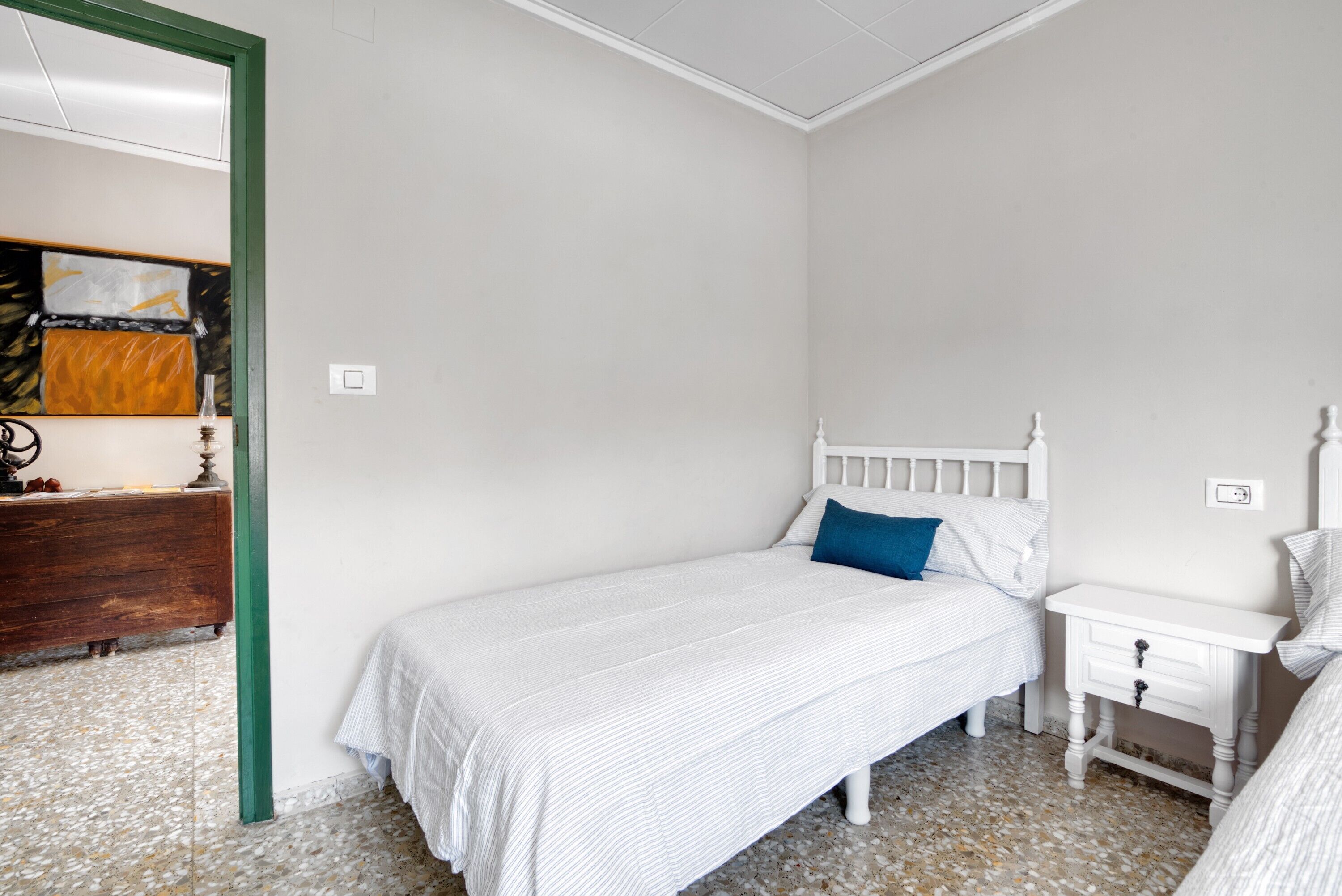 Une chambre à coucher avec un lit, une table de chevet, une commode et un chambranle de porte de couleur verte.