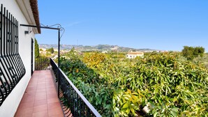 Un balcon donnant sur un jardin et sur des montagnes lointaines.