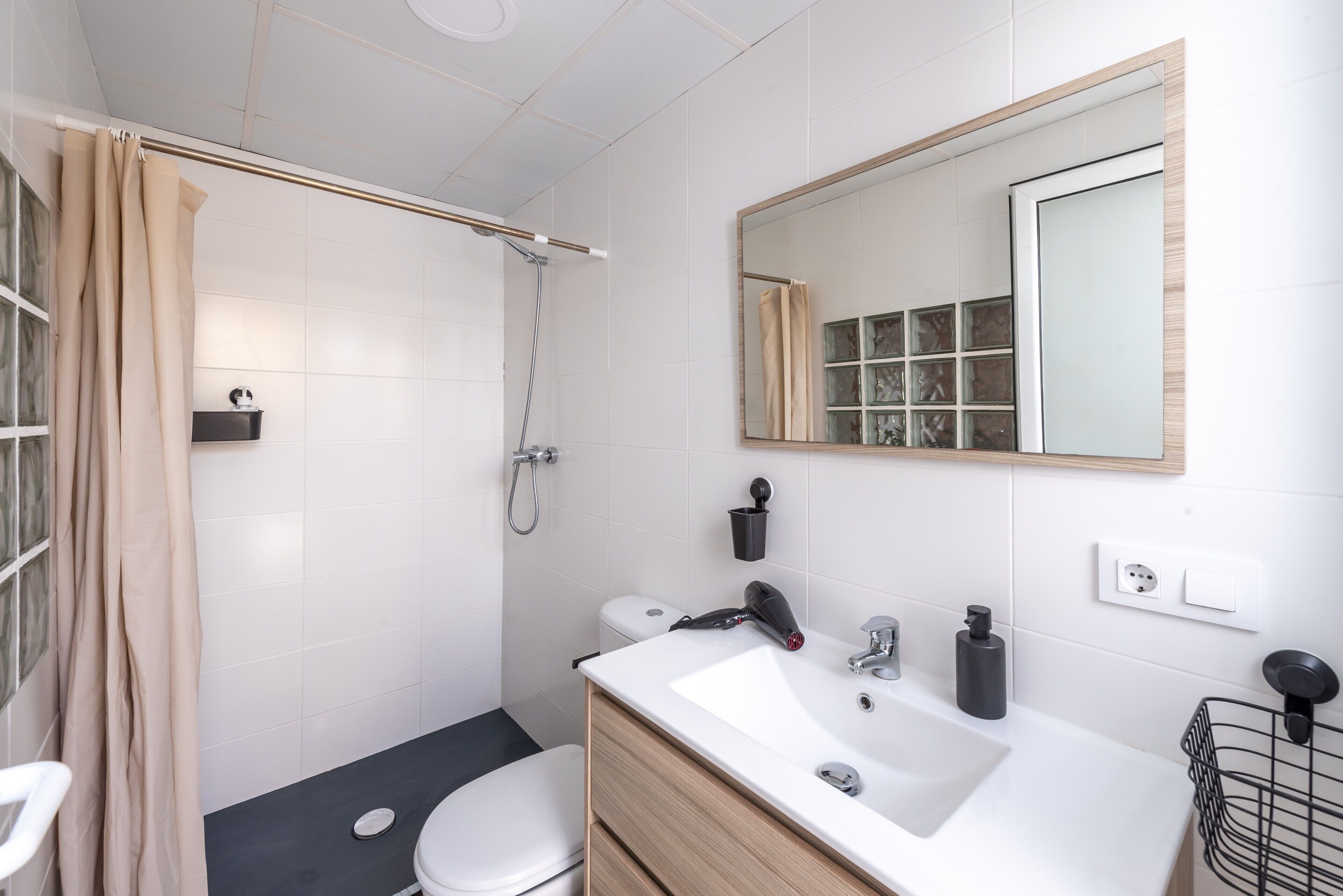 Un baño moderno con ducha, inodoro, lavabo y espejo.
