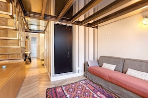 Een modern interieur met een houten receptiebalie, een bank met gestreepte kussens, een vloerkleed met dessin en een schuifdeur van glas.