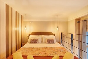 Een hotelkamer met een bed, twee bedlampen, een raam met gordijnen en uitzicht buiten.