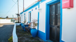 Un edificio con fachada azul y blanca, un buzón rojo y una planta en maceta.