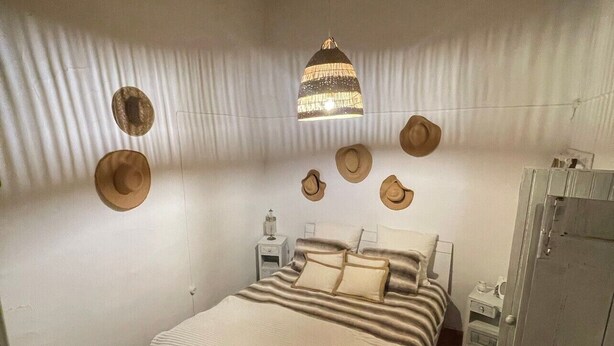 Un dormitorio con cama, mesita de noche, armario y ventilador de techo.