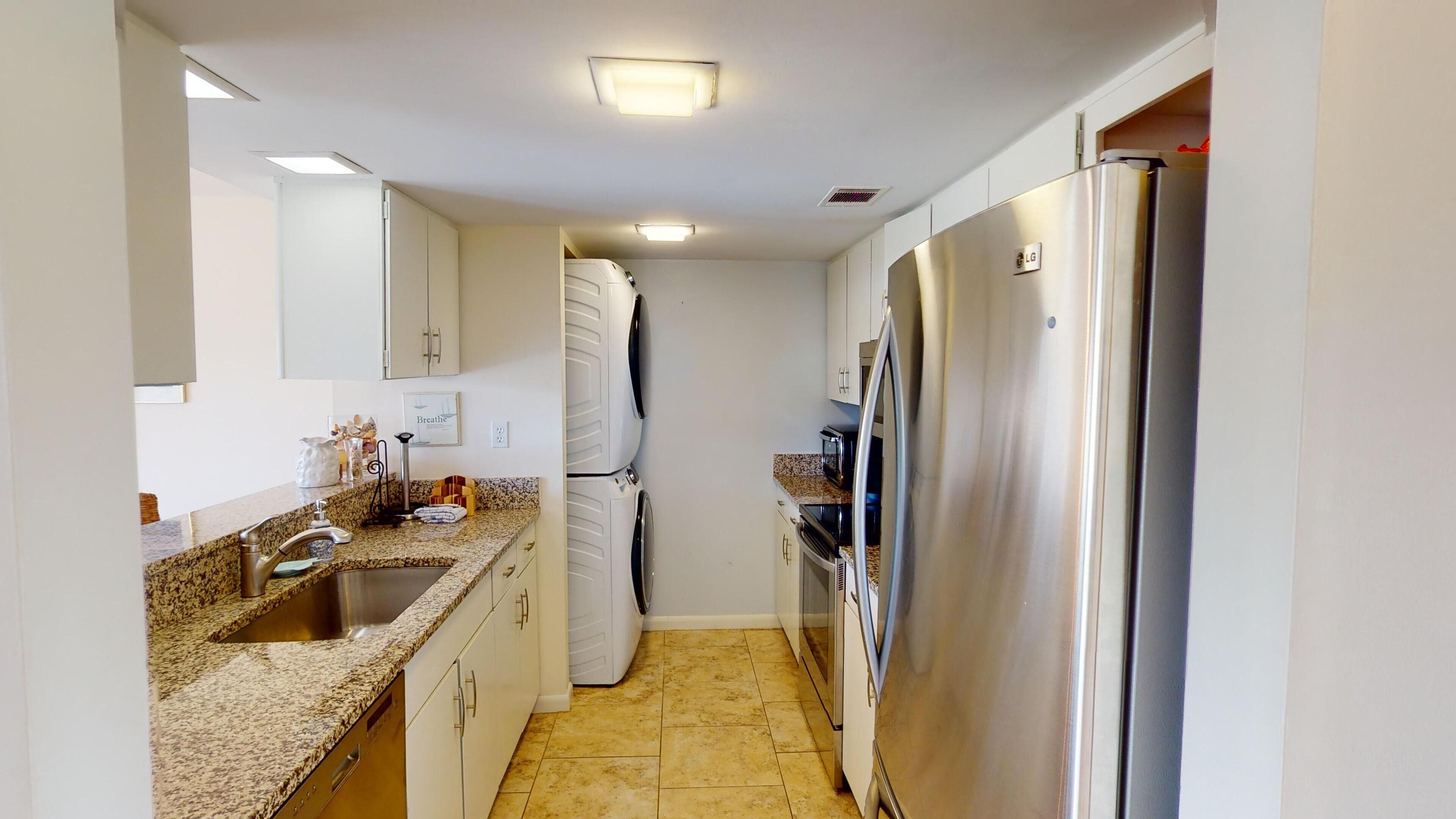 A compact kitchen with white cabinets, a stainless steel refrigerator, a microwave, and a built-in oven.