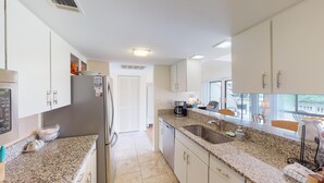 A modern kitchen with granite countertops, stainless steel appliances, and a view of the city.