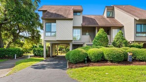 A two-story residential building with a driveway leading to the entrance, surrounded by well-maintained lawns and hedges.