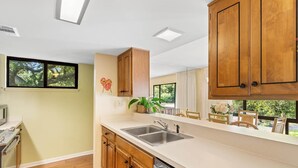 A modern kitchen with wooden cabinets, a double sink, and a view of the outdoors.