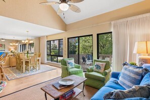 A spacious living room with a dining area, large windows with a view, and a ceiling fan. - Tranquil 2BR  Villa near Litchfield Beach (Pawleys Island)