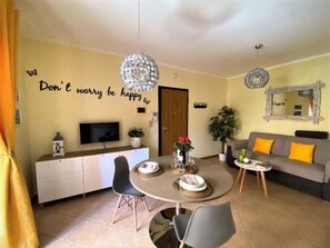 A cozy living room with a dining area, a sofa, a TV, and a motivational wall quote. - White Heron Residence (Ronchi dei Legionari)