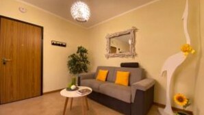 A living room with a sofa, a small round table, a potted plant, and a decorative mirror on the wall. - White Heron Residence (Ronchi dei Legionari)