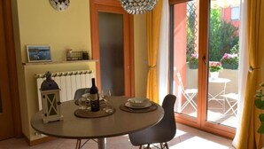 A dining area with a round table, chairs, a bottle of wine, glasses, a decorative lantern, and a clock on the wall. - White Heron Residence (Ronchi dei Legionari)