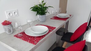Mesa posta com pratos, copos e uma planta em vaso.