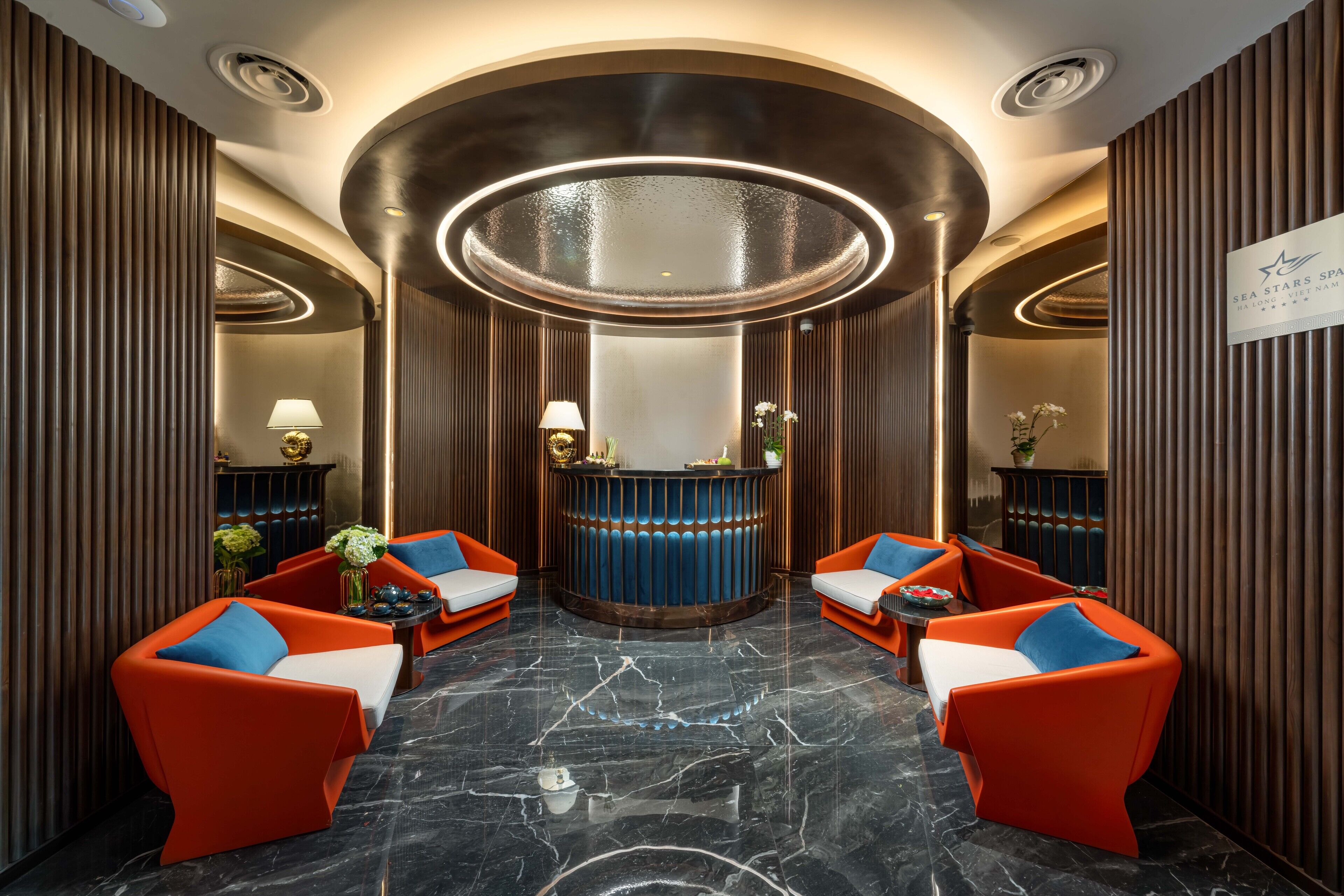 A lobby with a reception desk, two sofas with blue cushions, and a marble floor.