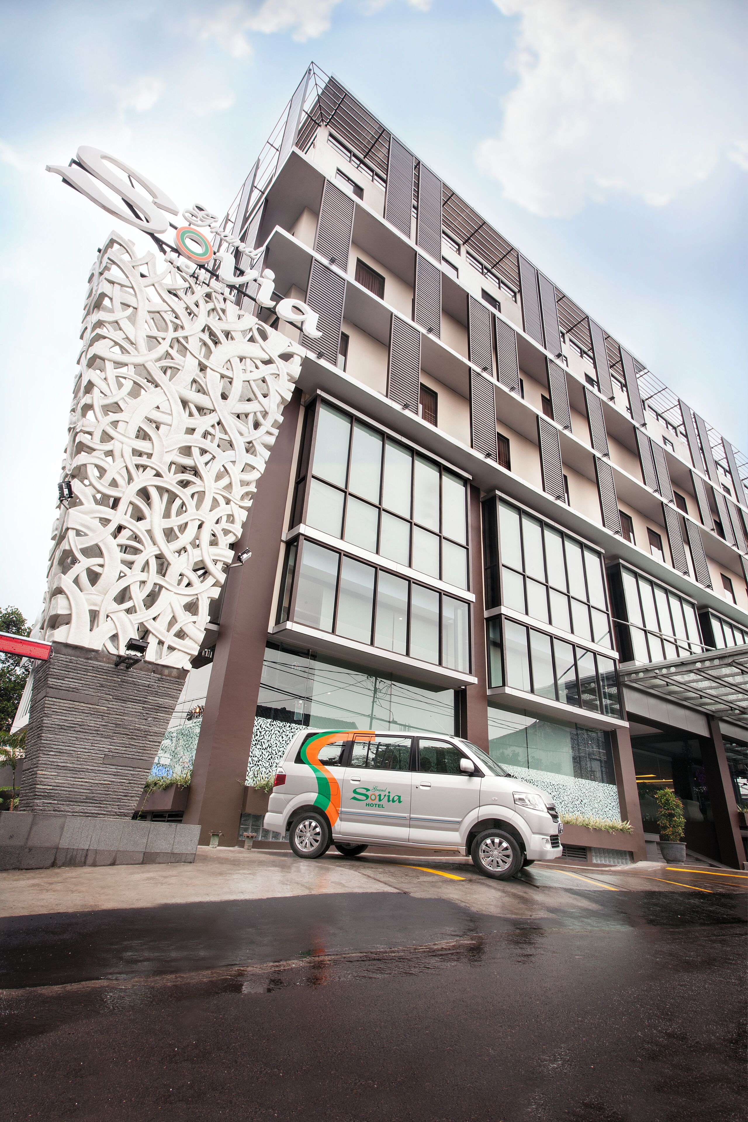 A modern building with a unique facade, a car parked in front, and a clear sky.