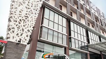 A modern building with a unique facade, a car parked in front, and a clear sky.