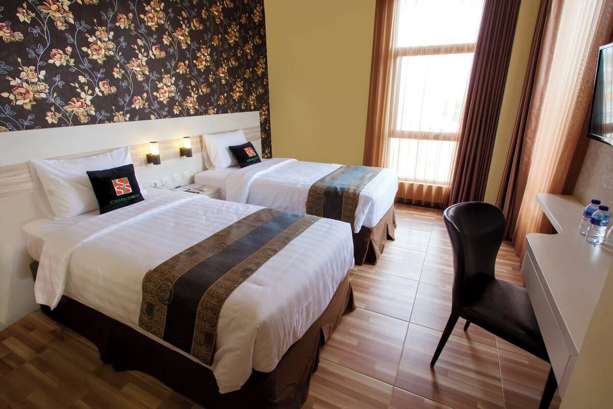 Ett hotellrum med två sängar, ett skrivbord och en stol.