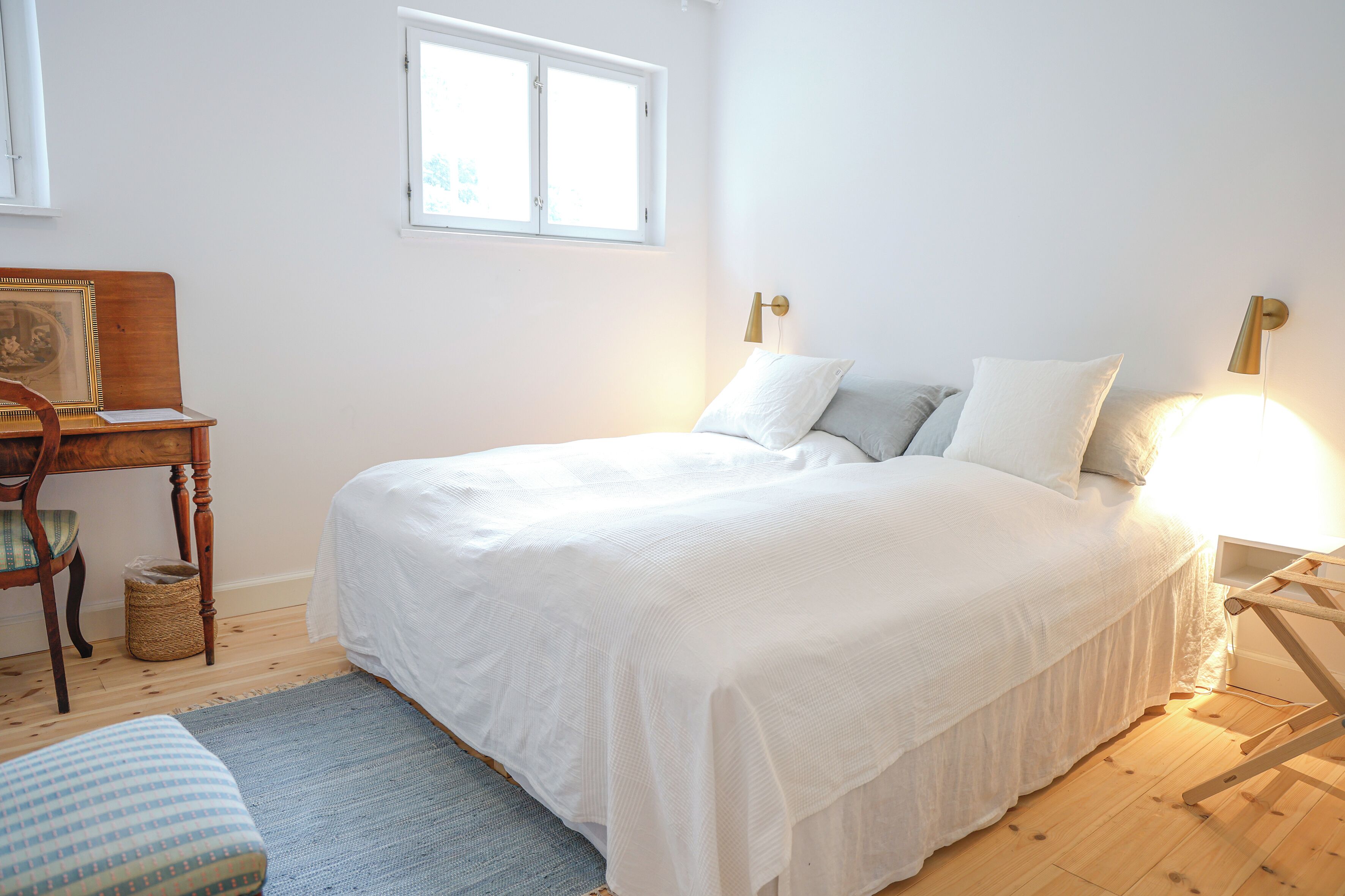 A bedroom with a large bed, a bedside table, a chair, and a window.