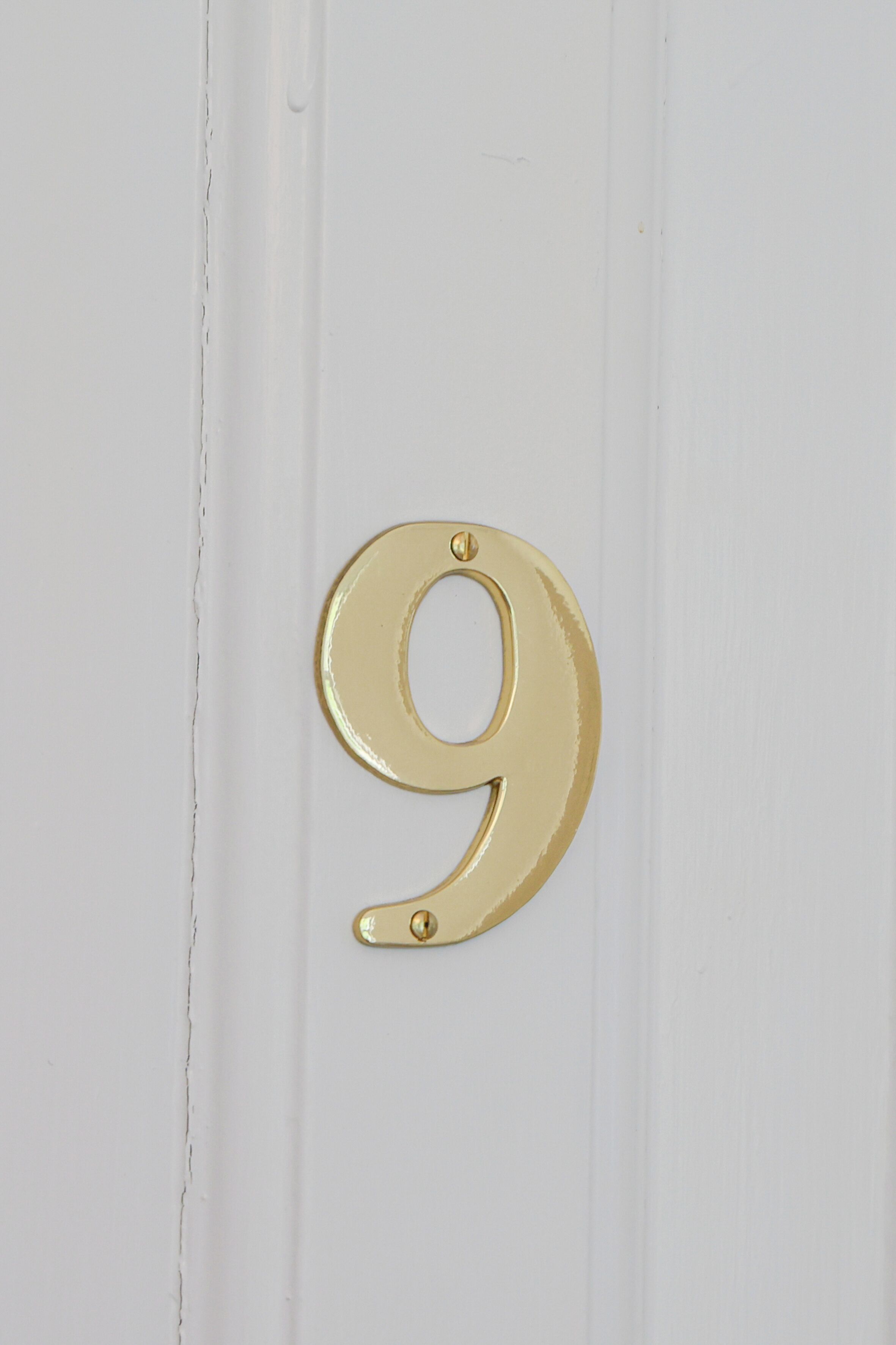 Una puerta blanca con un letrero dorado con el número 9.