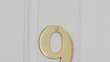 Una puerta blanca con un letrero dorado con el número 9.