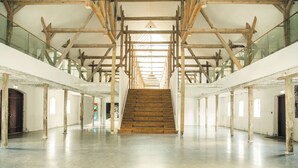 A spacious interior with a central staircase, wooden beams, and glass railings. - Lundsgaard Gods Badehotel (Kerteminde)