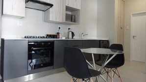 Una cocina moderna con horno integrado, un fregadero y una zona de comedor con dos sillas.