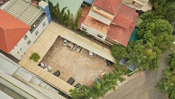 Vista aérea de un patio con zona de estacionamiento, rodeado de edificios con techos rojos y verdes.