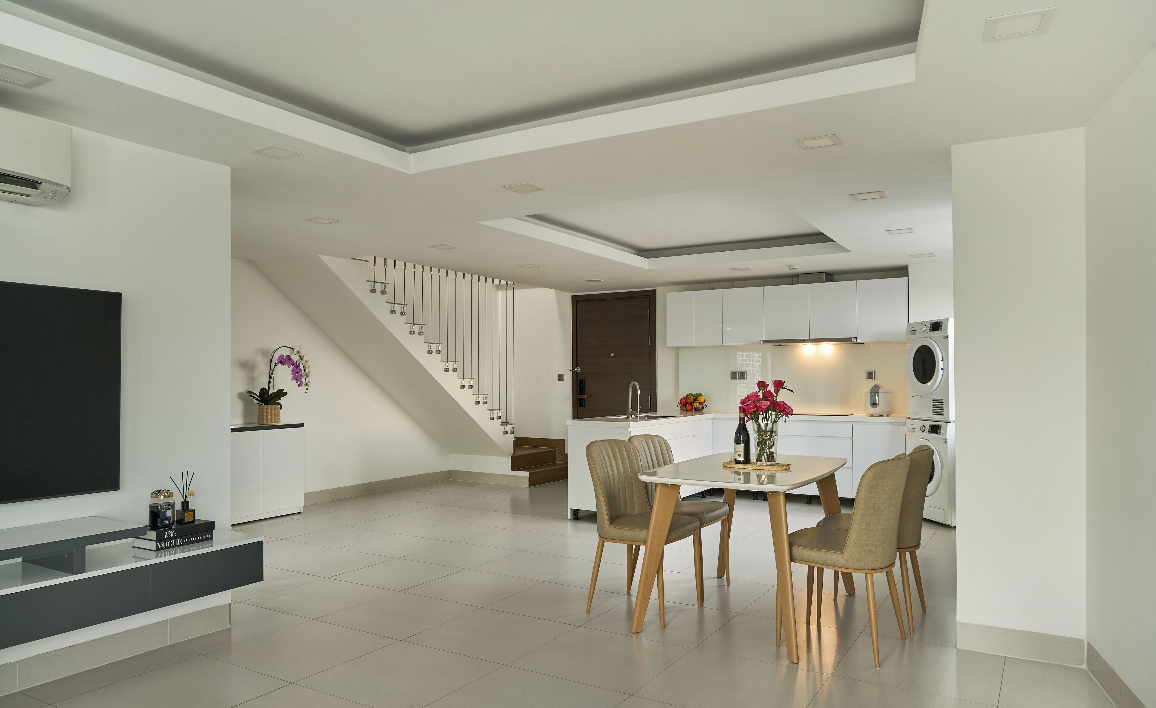 A modern kitchen with white cabinets, a built-in oven, and a dining area with a table and chairs.
