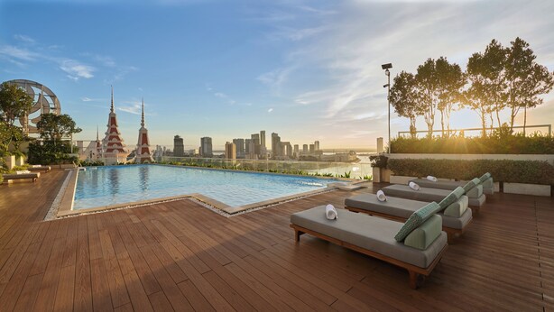 Zona de piscina en la azotea con vista al horizonte urbano, incluyendo una pagoda y edificios modernos.