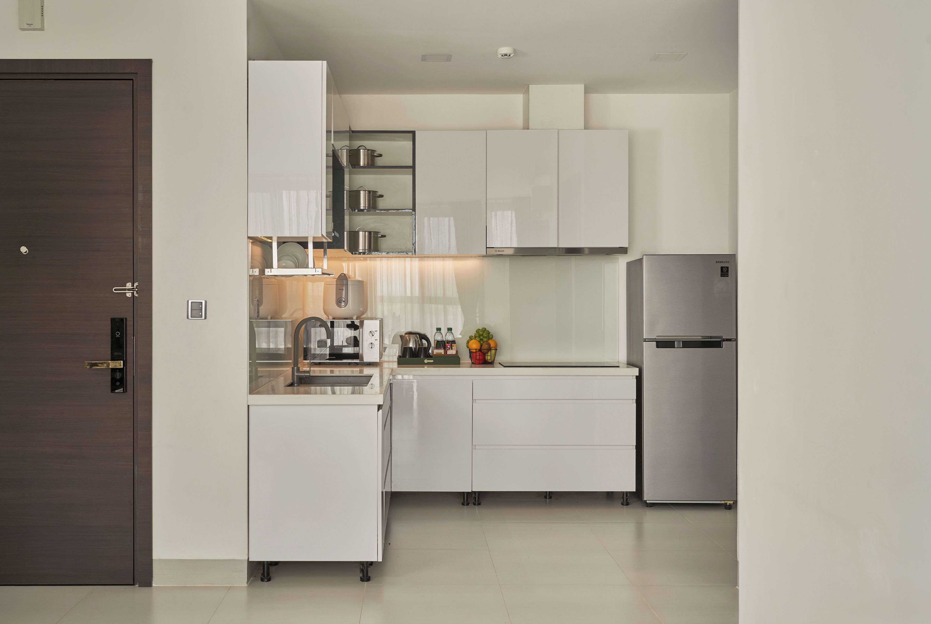 A modern kitchen with white cabinetry, a stainless steel refrigerator, and a built-in oven.