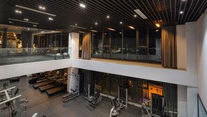 Un gimnasio de varios niveles con equipo de ejercicio y grandes ventanales con vistas a la ciudad.