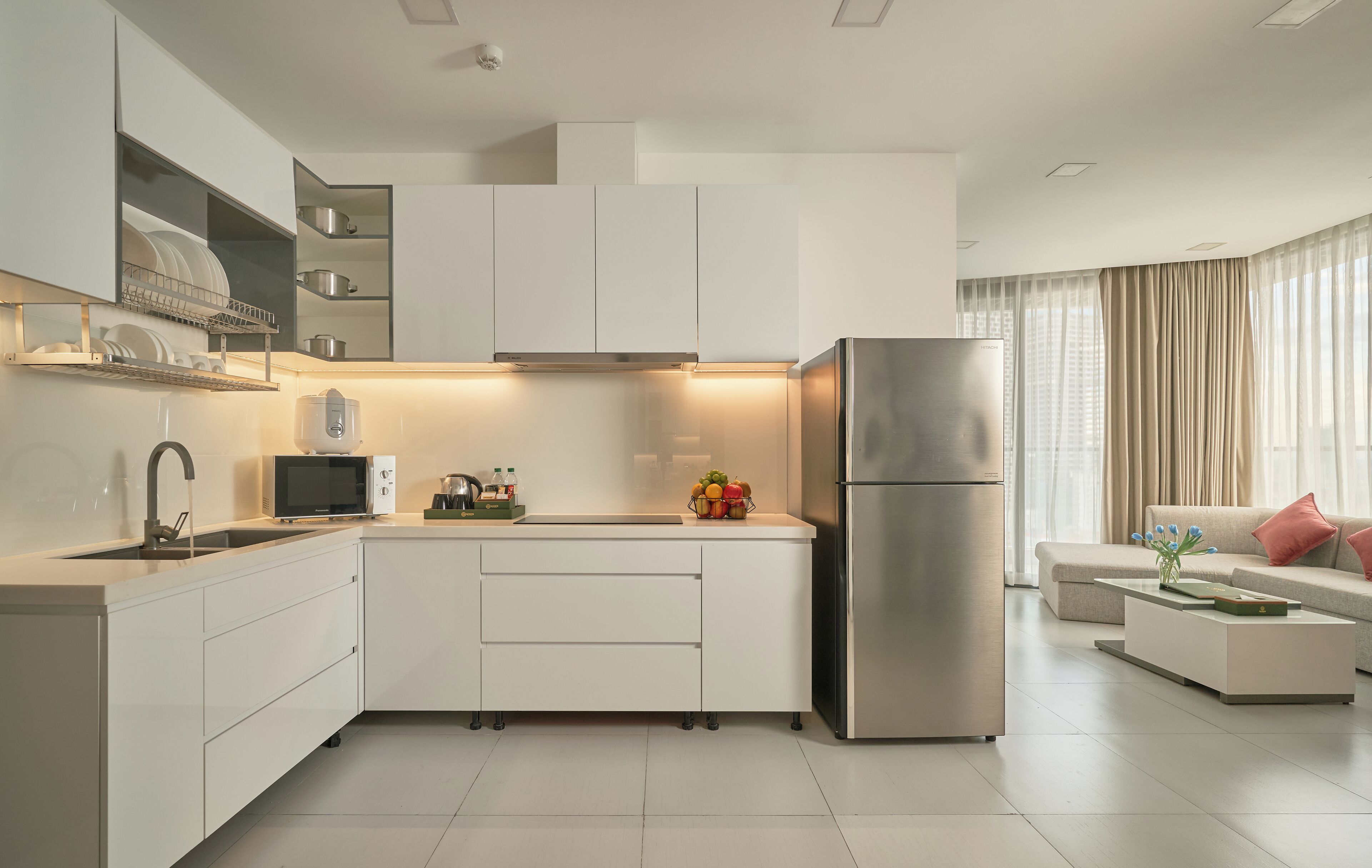 A modern kitchen with white cabinetry, a stainless steel refrigerator, and a microwave.