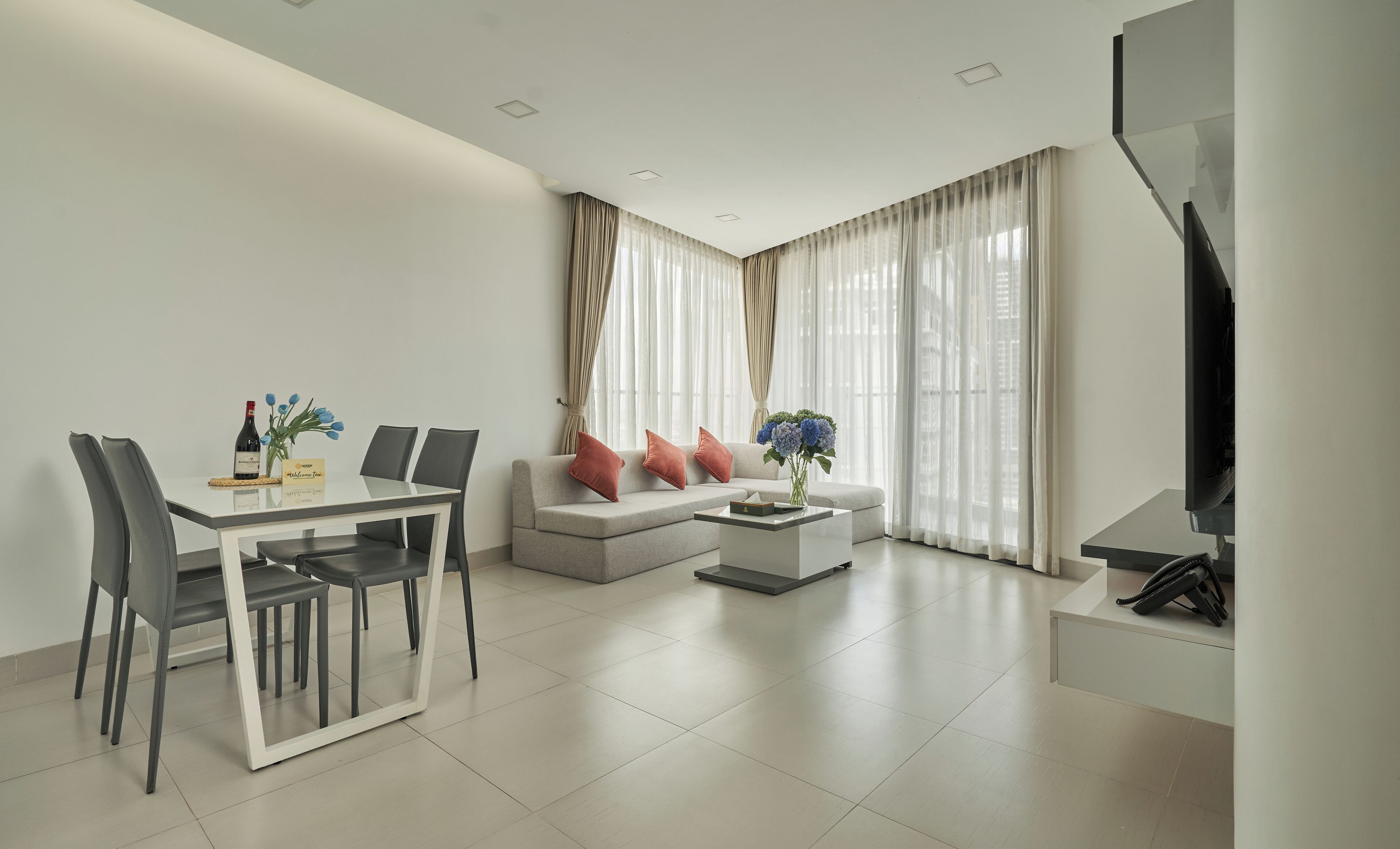 A modern living room with a dining area, a sofa set, a coffee table, and a TV.