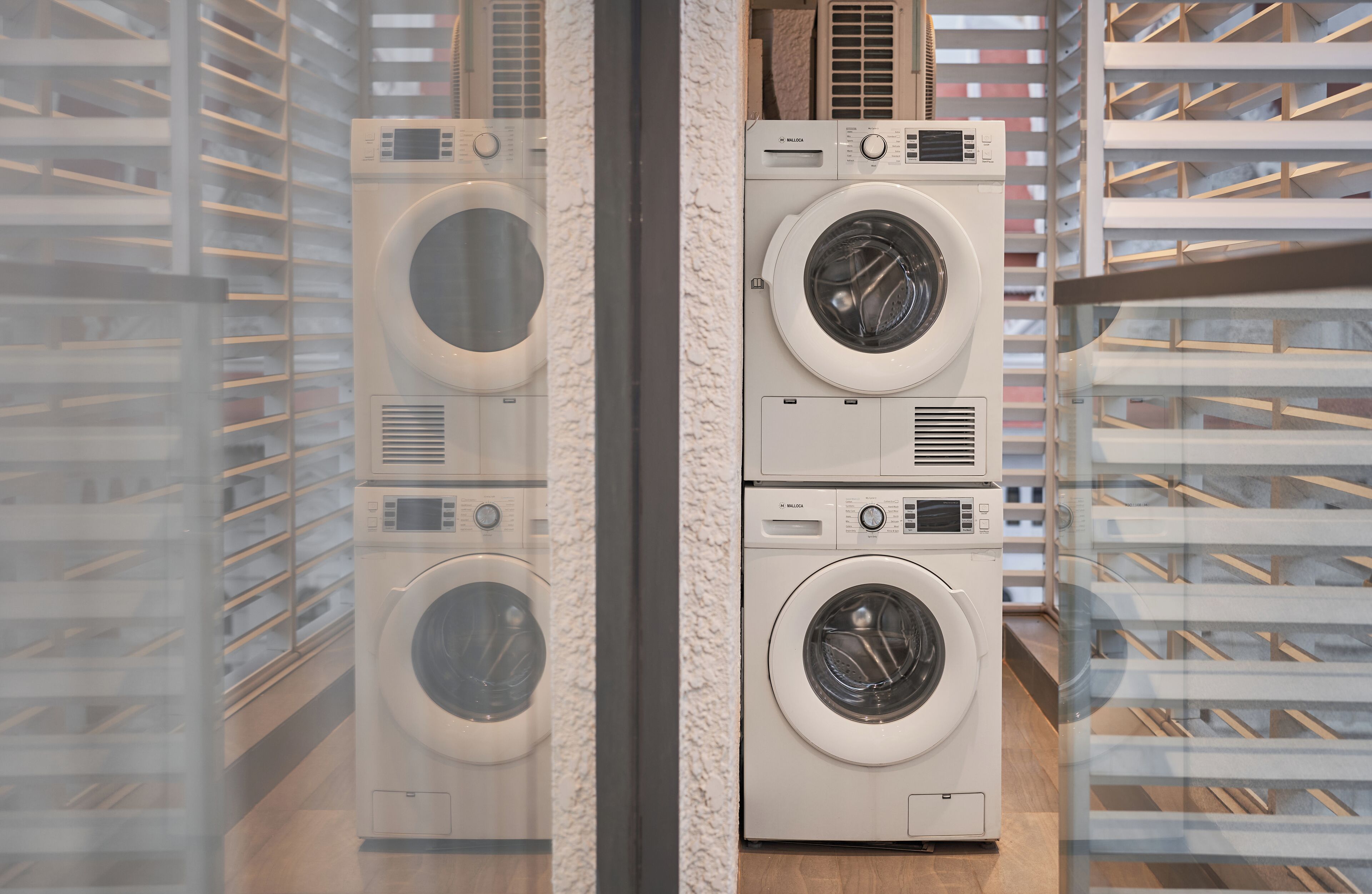 A laundry room with stacked front-loading washers and dryers.
