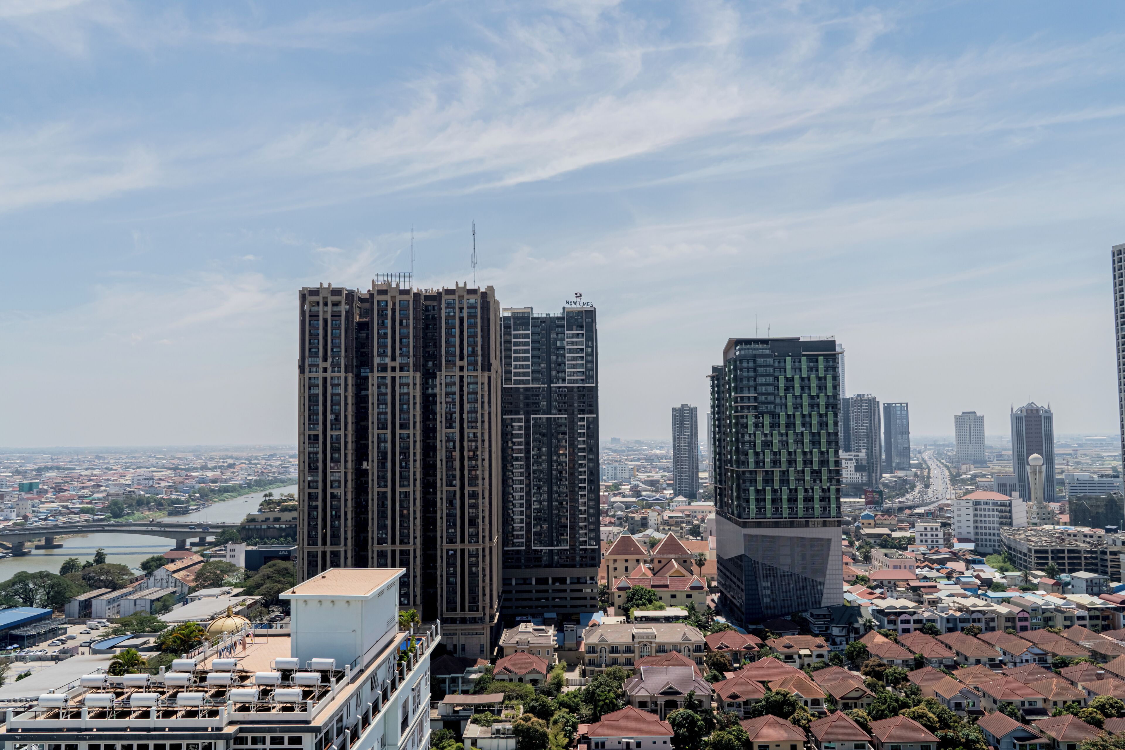 A high-rise building with a modern design, surrounded by smaller residential buildings and a river in the background.