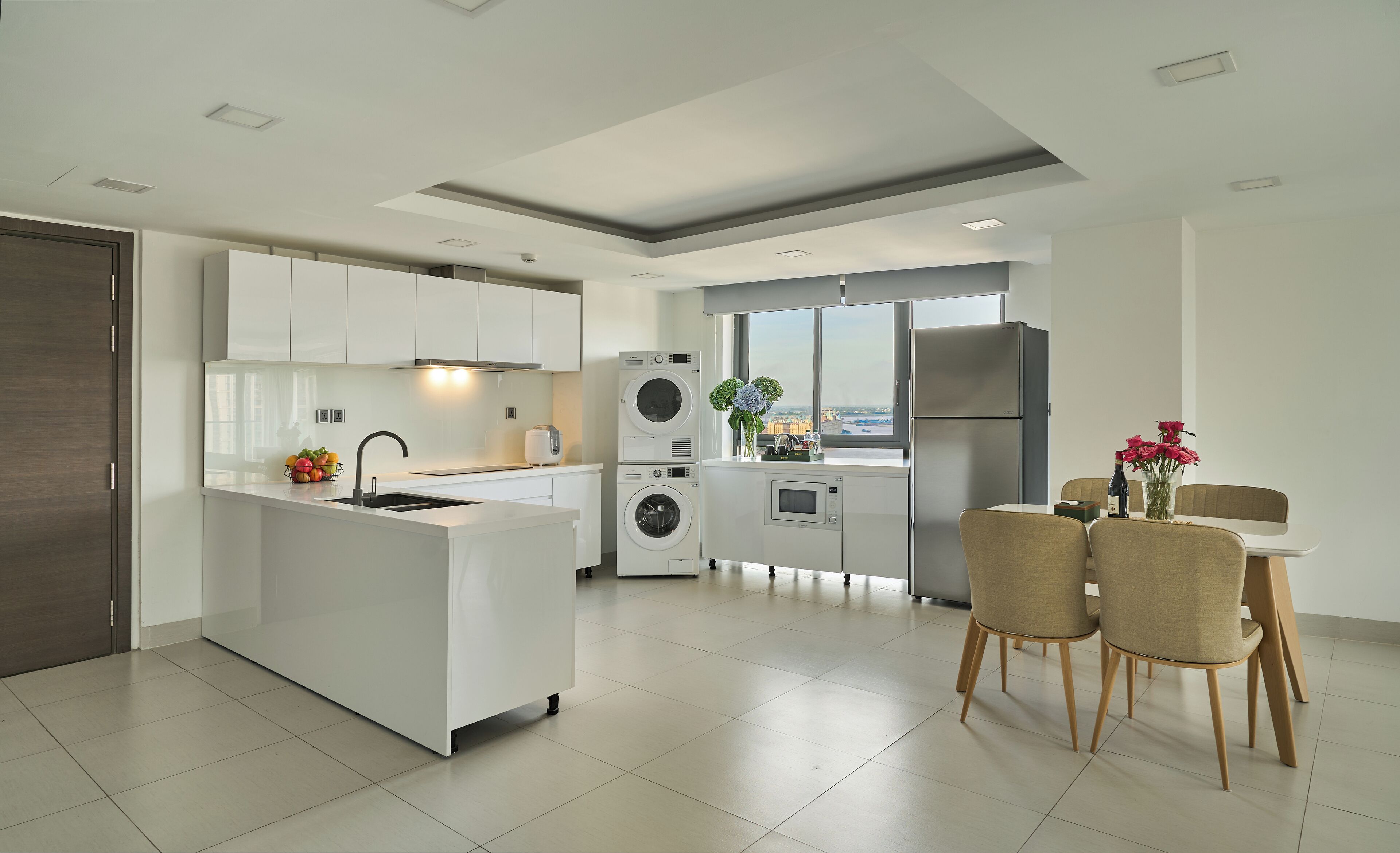 A modern kitchen with a central island, built-in appliances, and a dining area with a view.