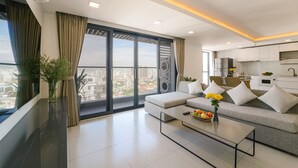 Un salón moderno con sofá, mesa de centro y vistas de la ciudad a través de amplias ventanas.