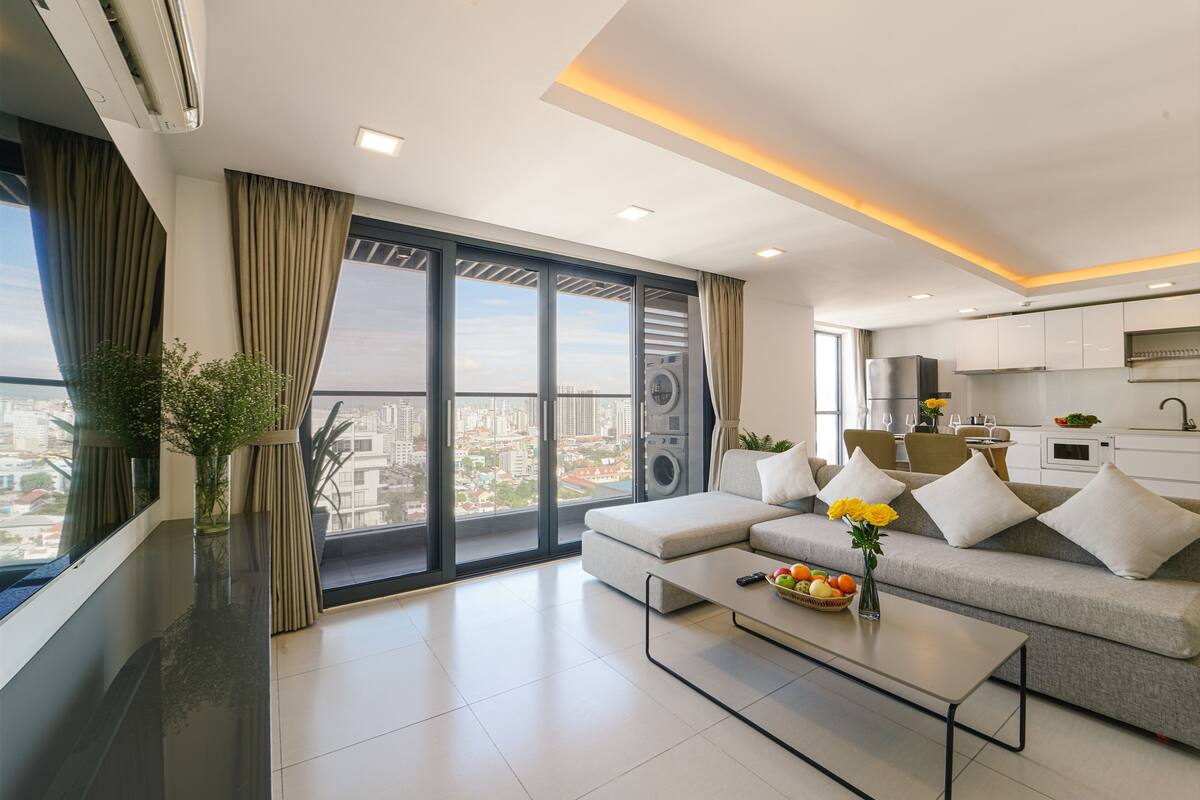A modern living room with a sofa, coffee table, and a view of the city through large windows.