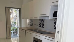 A modern kitchen with white cabinets, a built-in oven, and a stainless steel sink. - Panoramic penthouse with sea view (Positano)