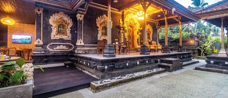 A traditional Balinese temple with ornate carvings, a covered seating area, and a stone pathway.