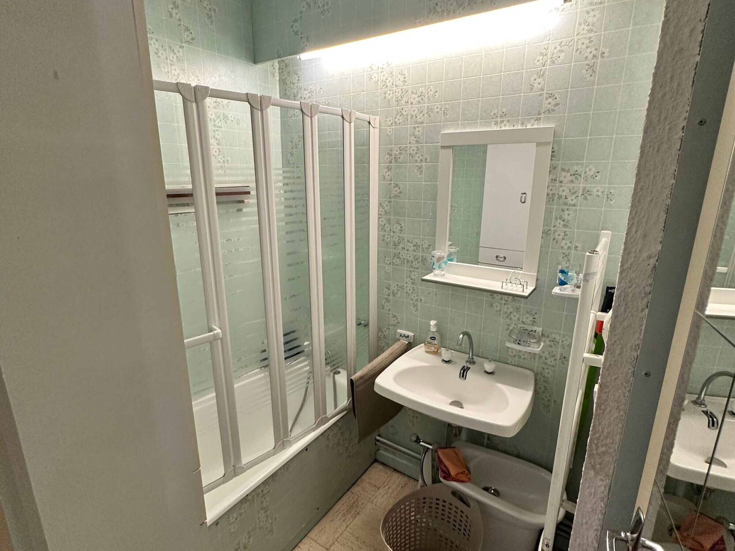A bathroom with a shower, two sinks, a mirror, and a window.