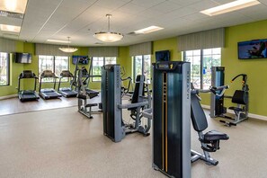 A gym with treadmills, weight machines, and a large mirror.
